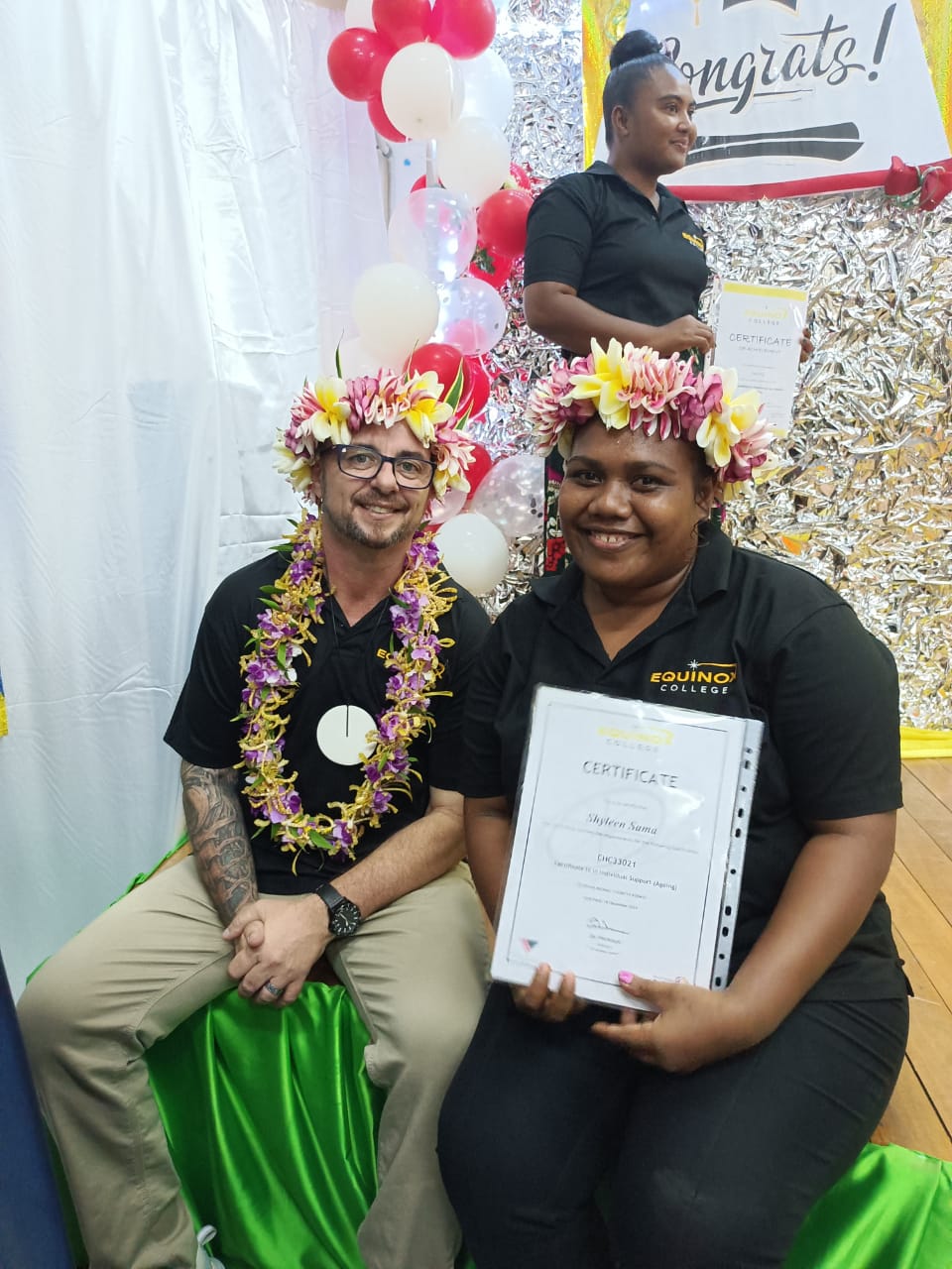 Graduate holding a certificate with Equinox College staff