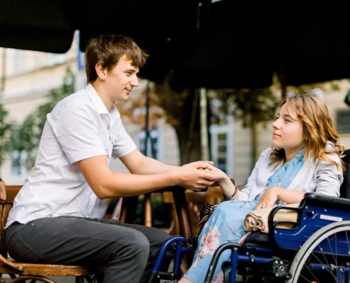 person in wheelchair holding hands with another person